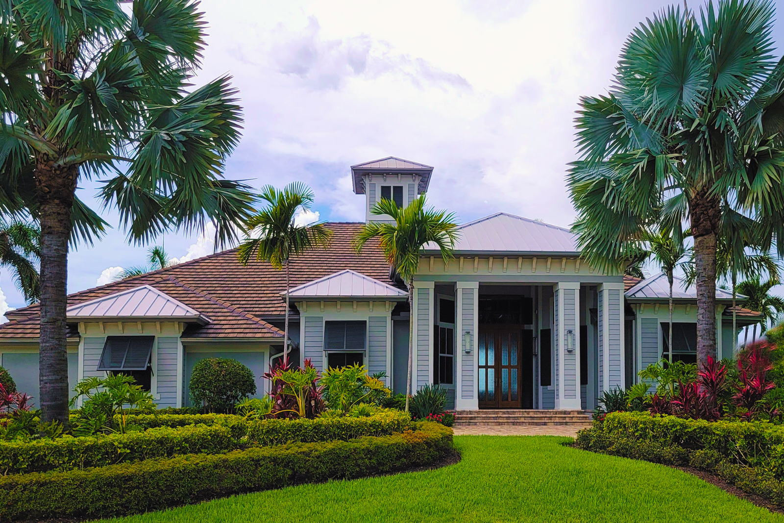 Coral Gables home with new impact windows and doors framed by palm trees at dusk